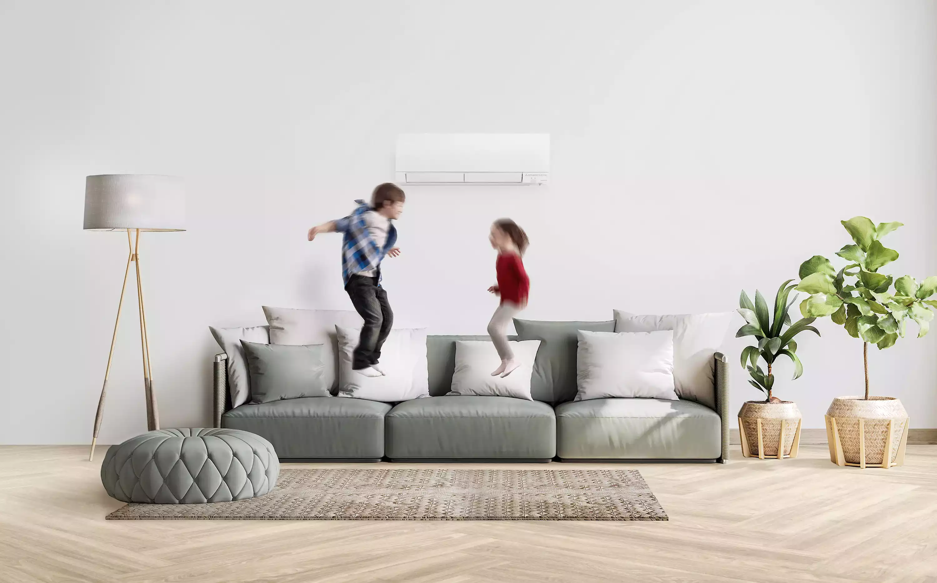 Deux enfants sautent sur un canapé sous un climatiseur mural dans un salon moderne et lumineux.